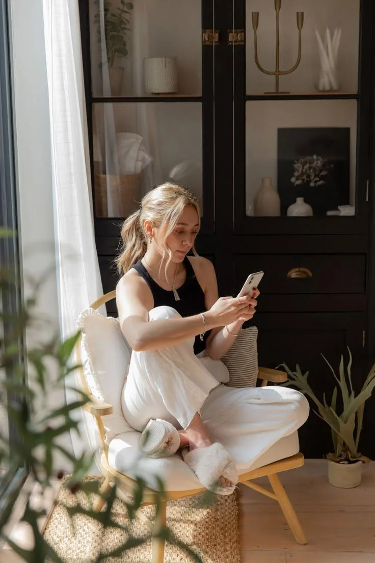 A woman relaxing in a chair at home, texting her health guide